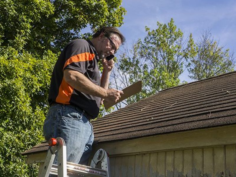 Roof inspector assesing storm dammage to shingles.