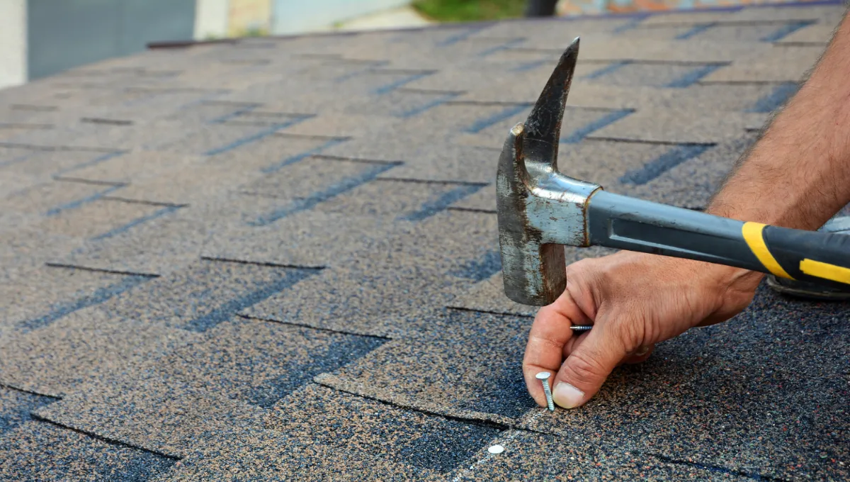 Roofer installing shingles on roof.
